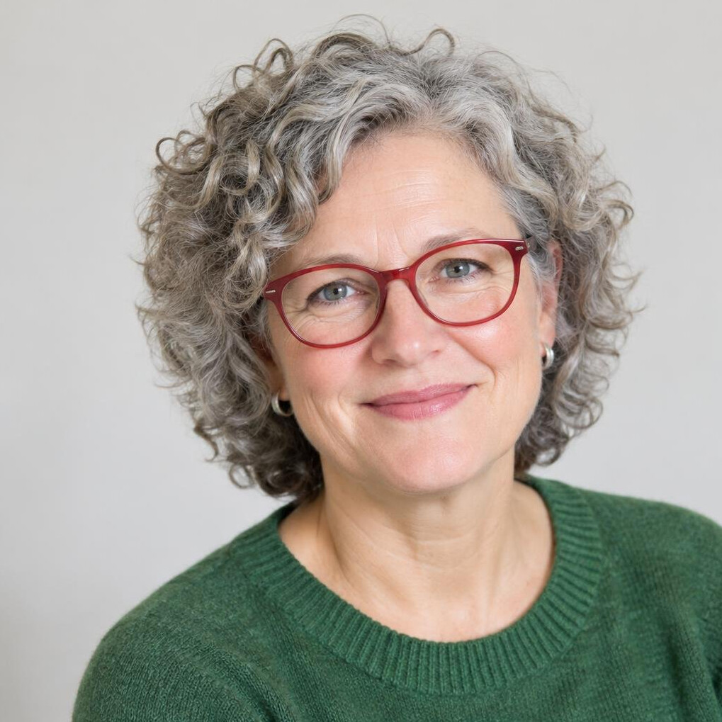Friendly woman in her fifties with curly grey hair and glasses